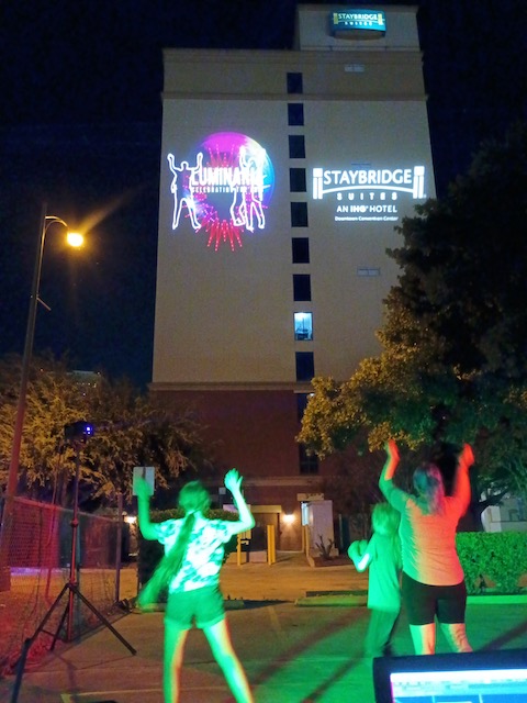 Dancers at Luminaria have their images projected in laser light